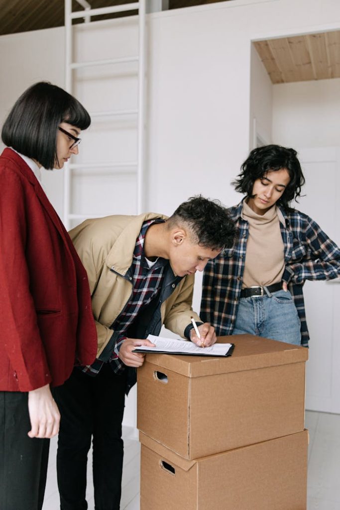 Three young adults collaborating on moving plans in a modern apartment.